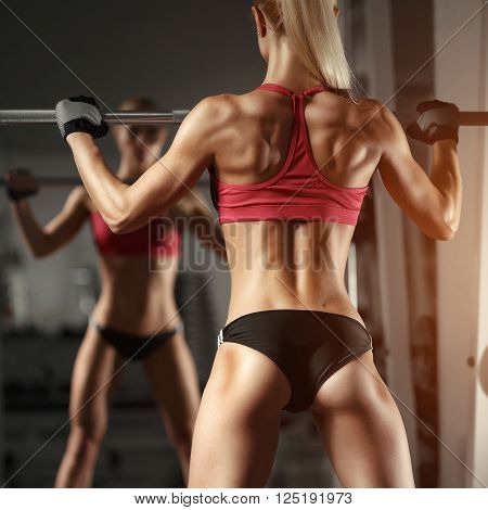 Beautiful fitness sexy woman doing squat workout in gym. Fitness, sport, powerlifting and people concept