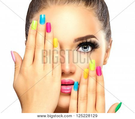 Beauty Girl Face with Colorful Nail polish. Colourful Studio Shot of young Woman. Vivid Colors. Colourful Manicure and fashion Makeup. Rainbow Colors. Beautiful lady touching face. Isolated on white