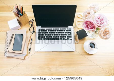 Girly office desktop with blank laptop screen flowers coffee smartphone and various office tools. Mock up