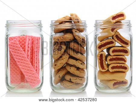 Three glass jars filled with cookies, on a white background with reflection. Jars contain, pink sugar wafers, chocolate chip and fruit bars.