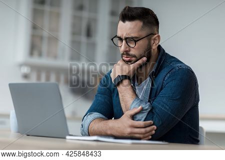 Thoughtful Businessman Think Of Online Project, Look At Laptop At Workplace, Professional Consider S