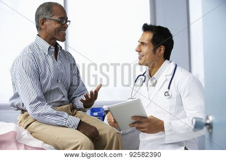 Doctor In Surgery With Male Patient Using Digital Tablet