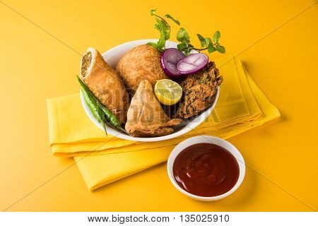 coriander vada or kothimbir vada, samosa, kachori, daal vada on brown wooden planks. indian assorted snacks. Indian snacks combination. Indian snacks group, indian favourite snacks, asian spicy snacks