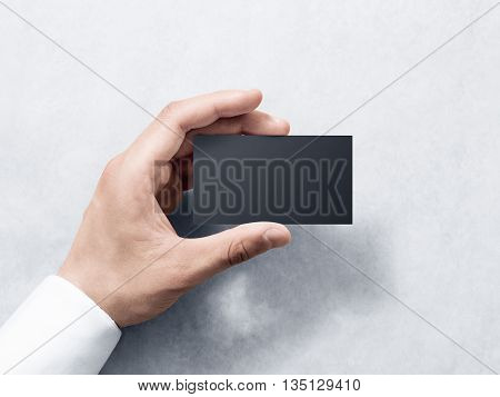 Hand hold blank plain black business card design mockup. Clear calling card mock up template holding arm. Visit pasteboard paper surface display front. Check small offset card print. Business branding