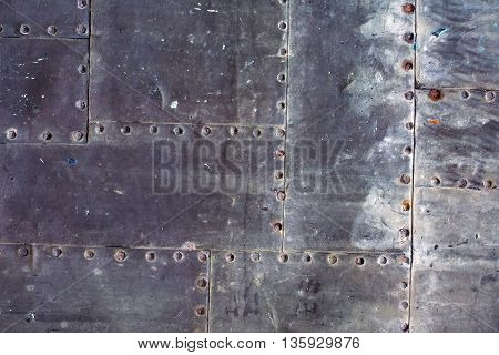 Old rusty grunge steel fragment of metal sheets assembled with rivets on armor textured background