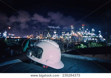 White Safety Helmet And Ear Muff On Industrial Plant Background, Worker Concept In Petrochemical Ind