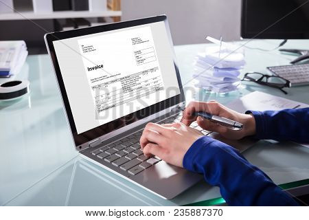 Businessperson Analyzing Invoice On Laptop