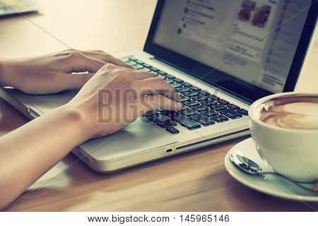 Close up young woman working on laptop computer in coffee shop.Rear view of business woman using laptop computer.Working concept.Vintage tone.