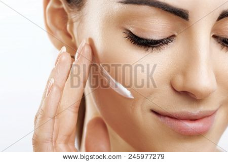 Closeup Happy Young Woman Applying Cream To Her Face Skincare And Cosmetics Concept. Cosmetics. Woma