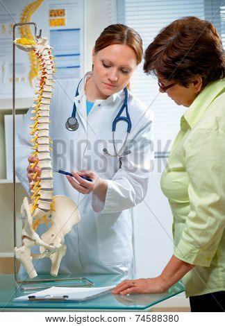 Physical Therapist shows the problem areas on the model of the spine to patient and explains the cause of her pain.