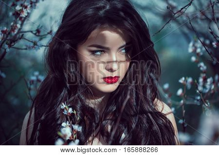 Fashion Art Mystical Spring Model Girl Portrait in Moonlight Night. Sexy Glamour Summer Beautiful Woman with Healthy and Beauty Brown Hair with flowers over nature blurred background. Fairy