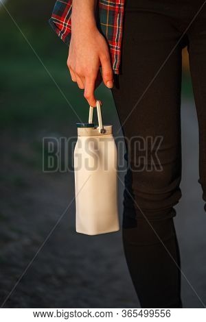 Eco-friendly Bottle. Reusable White Bottle With Water On The Finger Of The Hand . Folding Bottle.