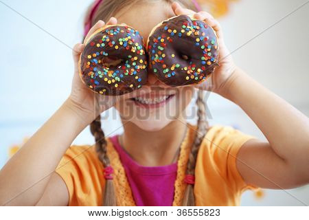 Cute kid girl eating sweet donuts