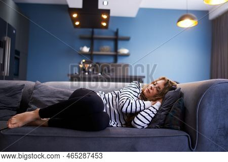 Girl Sleeps On Cozy Sofa In Living Room At Siesta Time. Sleeping Woman Taking Nap On The Sofa During