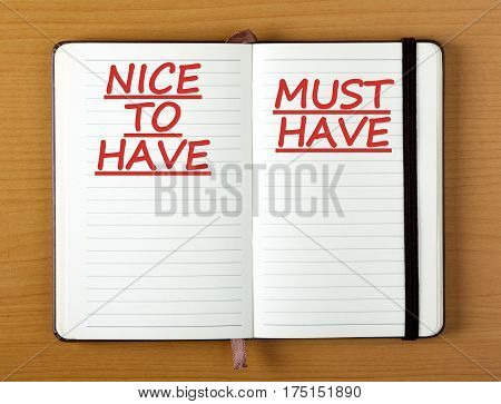 A notebook with the headings Nice To Have and Must Have as a reminder when making decisions in business or life there are priorities to consider