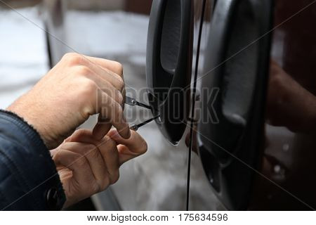 Closeup view of carjacker trying to open  car with pick-lock