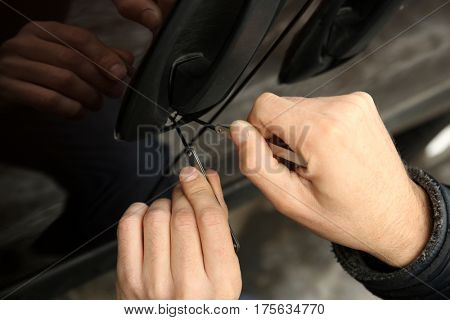 Closeup view of carjacker trying to open  car with pick-lock