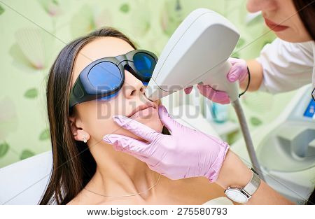 Doctor Cosmetologist Conducts The Procedure Of Laser Hair Removal From The Body Of A Girl