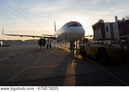 A Jet Bridge Connecting To An Airplane At Sunset