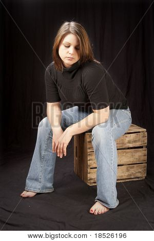 depressed teenaged girl seated on box