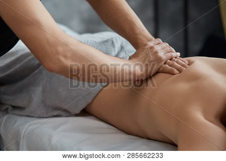 Young Handsome Man Enjoying A Back Massage. Professional Massage Therapist Is Treating A Male Patien