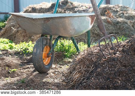 Ecological Organic Fertilizer To Accelerate Plant Growth. Large Pile Of Manure, Pitchfork And Garden