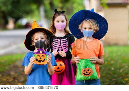 Kids Trick Or Treat In Halloween Costume And Face Mask. Children In Dress Up With Candy Bucket In Co