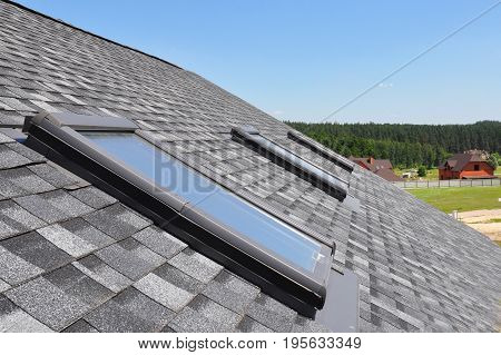 Attic skylight. Asphalt Shingles House Roofing Construction with Attic Roof windows skylights waterproofing.