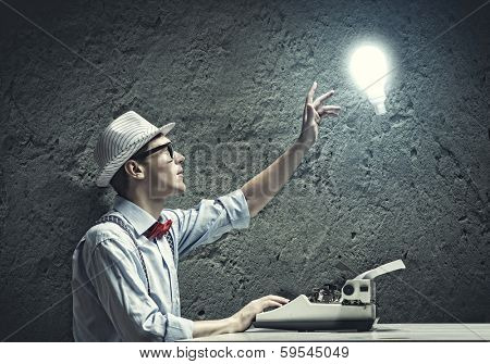 Young funny man in glasses writing on typewriter