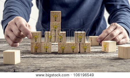 Front View Of A Man Arranging Wooden Blocks With Hand Drawn Yellow Lightbulb In A Random Structure