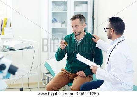 Professional therapeutist or other clinician talking to patient with pill-bottle