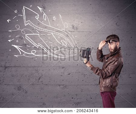 A hipster guy opening his point of view through looking a vintage camera concept with illustratied drawn arrows on urban wall