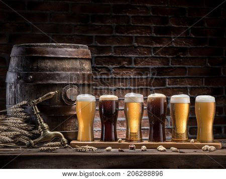 Glasses of beer and ale barrel on the wooden table. Craft brewery. Beer background.