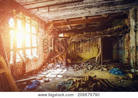 Inside ruined abandoned house building after disaster, war, earthquake, Hurricane or other natural cataclysm, sun light in dark dirty room