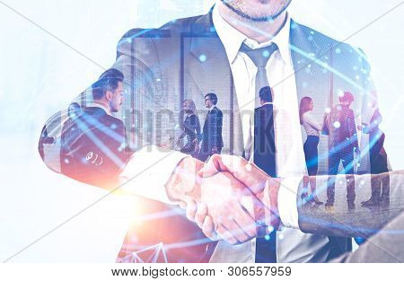 Handshake Of Business People With Double Exposure Of Their Team Working In Office. Global Digital Ne