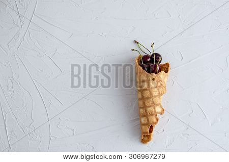 Ice Cream Cone Filled With Cherries On A Light White Concrete Background.