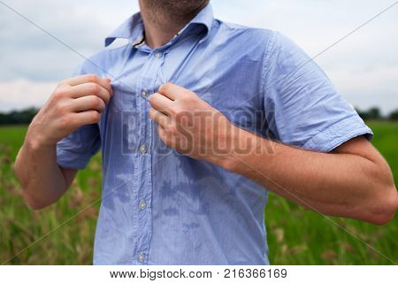 Man with hyperhidrosis sweating very badly under armpit in blue shirt because of hot weather. Travelling in asia thailand with backpacker