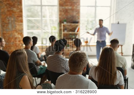 Male Speaker Giving Presentation In Hall At University Workshop. Audience Or Conference Hall. Rear V