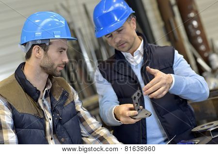 Engineer with mechanical worker checking on production