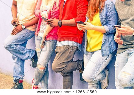 Multiracial group of friends texting sms and looking down to cell phone - Interracial students hands using mobile - Concept of young people addiction to web technology - Focus on hand of red hair girl