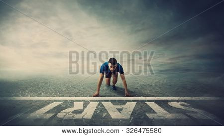 Determined Man Runner Standing In Running Position, At The Start Line, Looking Ahead Confident. Youn