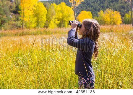 Explorer binocular looking kid girl in yellow autumn nature outdoor