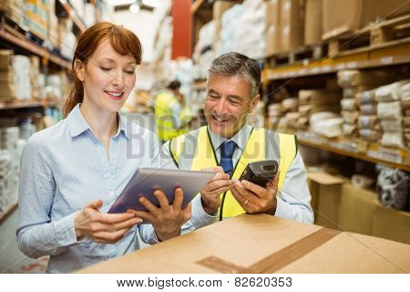 Warehouse managers looking at tablet pc in a large warehouse