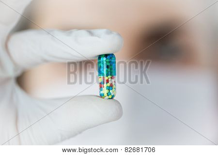 science, chemistry, biology, medicine and people concept - close up of young female scientist or doctor holding and showing pill in laboratory