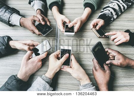 Group of friends having fun together with smartphones - Closeup of hands social networking with mobile phones - Technology and phone addiction concept - Soft focus on bottom hands - Vintage filter