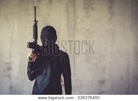 Terrorist Holding Rifle Gun On Grunge Wall. Social Issued Theme. Terrorist And Robber Concept. Polic