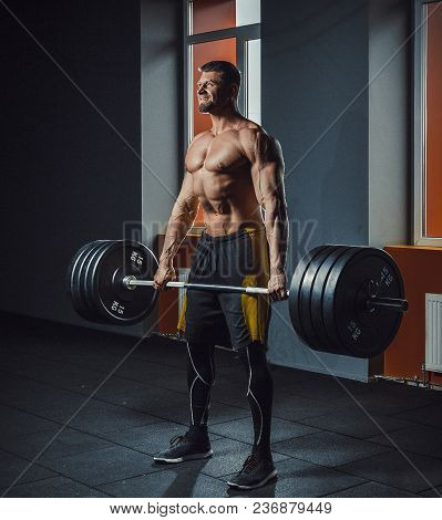 European Caucasian Athletic Man Doing Deadlift With Heavy Barbell. Man Lifting Barbell Opposite Wind