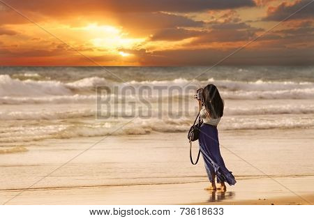 Woman Taking a Picture on the Beach at Sunset