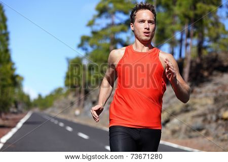 Sprinting runner man running at fast speed. Male sport sprinter training hard. Young strong male fitness model during run outdoors in beautiful landscape.