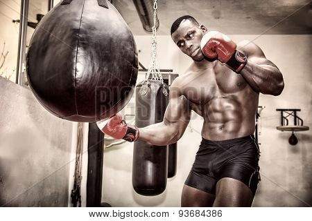 African male boxer punching ball wearing boxing gloves